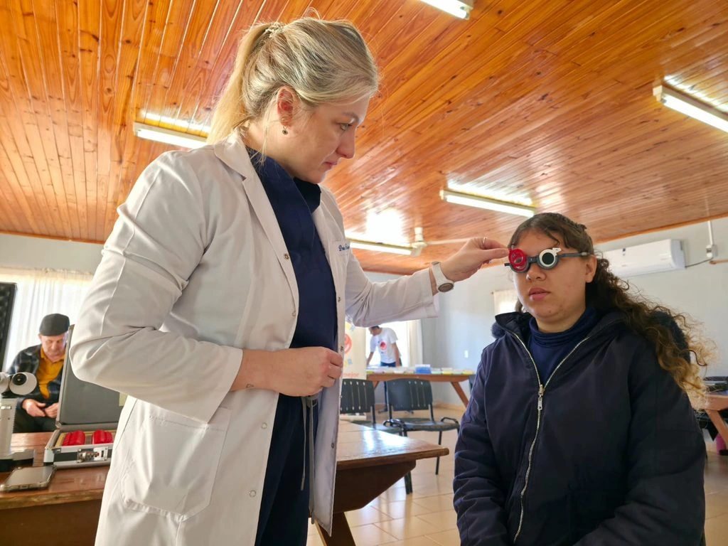 Oftalmólogo prueba lentes graduados a una joven vecina durante el operativo.