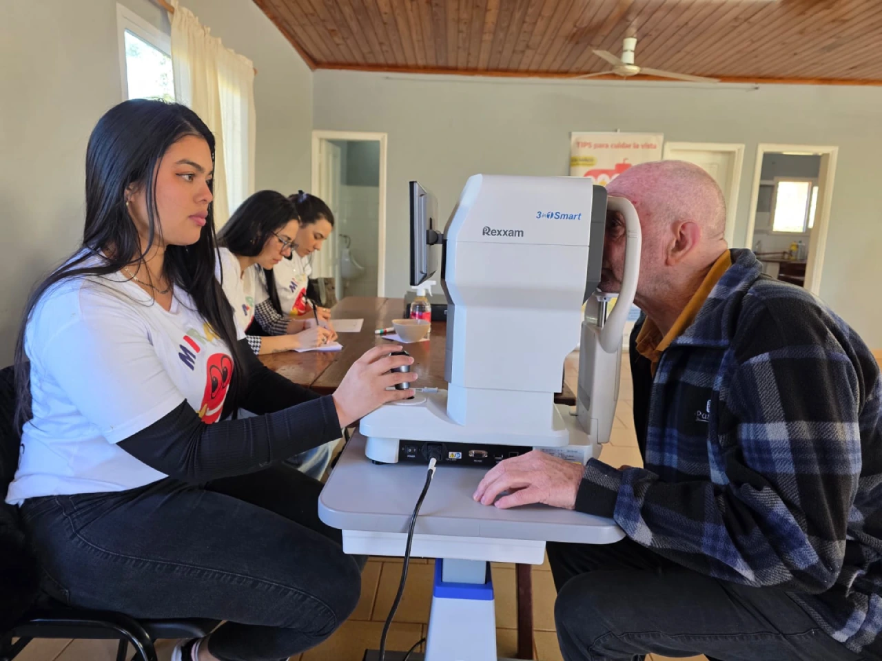 Oftalmóloga revisa los ojos de un vecino mayor mediante un autorefractómetro. Mirar Mejor en General Alvear.