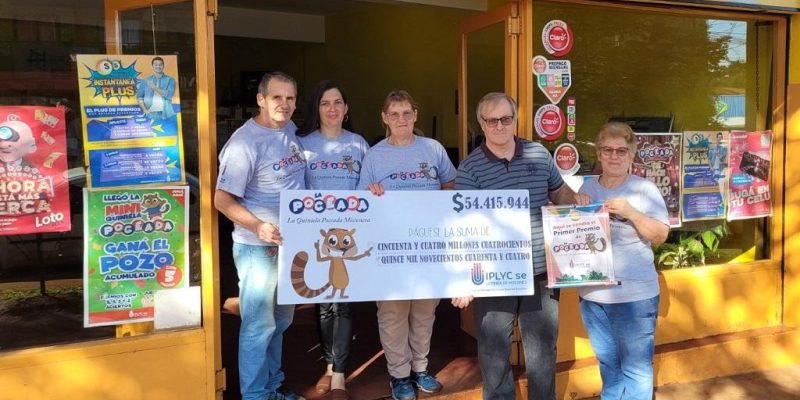 Equipo de la Agencia 316, frente al local, muestra sonriente el cheque del premio millonario de la Poceada Misionera.