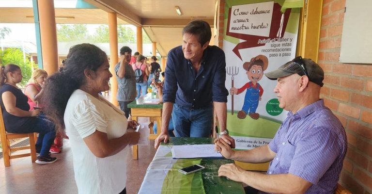 Vecina charla con Héctor Decut y un colaborador sobre huerta.