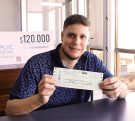 Lucas Balbuena, muestra sonriente su cheque. Invertirá el dinero en elementos para su carpintería.