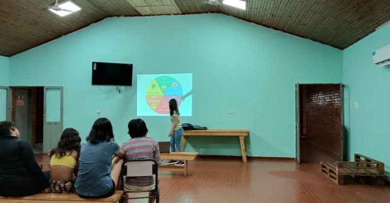 psicóloga del equipo de Juego Responsable explica un gráfico estadístico a jóvenes del hogar Papa Francisco.