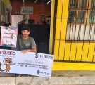 Marcelo Valenzuela, vendedor del primer premio, muestra el cheque sentado en la puerta de la Agencia.