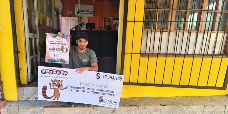 Marcelo Valenzuela, vendedor del primer premio, muestra el cheque sentado en la puerta de la Agencia.