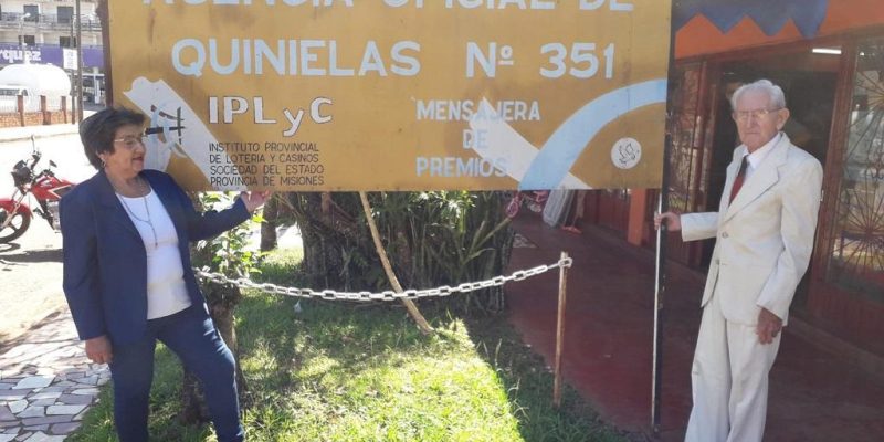 Kusy Ceslao y su esposo frente al cartel de su agencia.