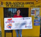 vendedora de la Mini Poceada millonaria frente a la sub agencia muestra sonriente el cheque